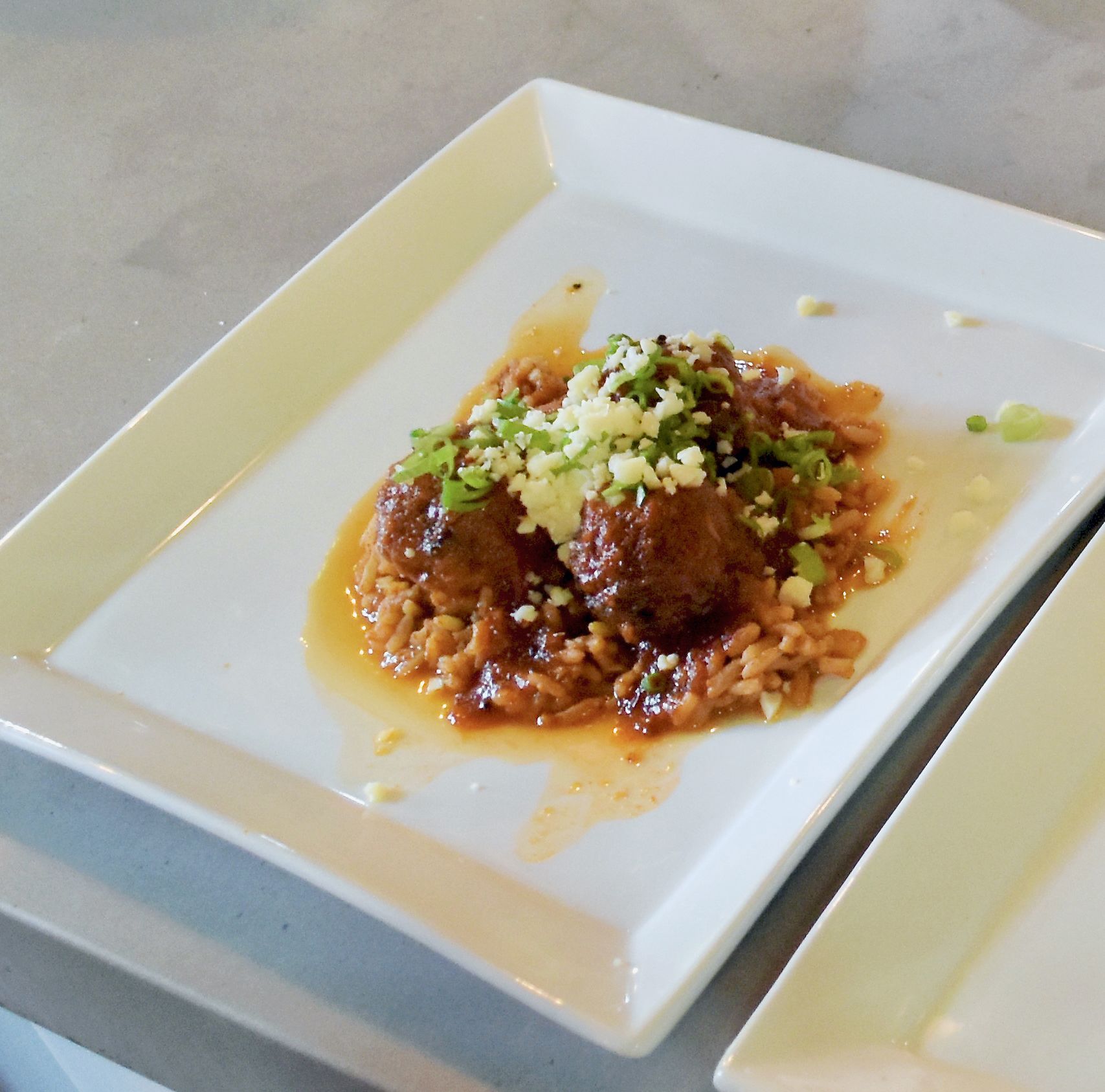 Chicken meatballs over rice with cotija cheese and green onion.
